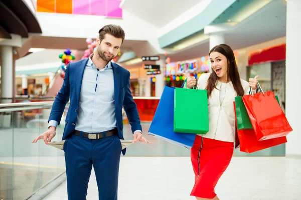 E 'tempo di shopping con vendite e divertimento. Carino allegro successo felice bella coppia in giacca con borse della spesa colorate, puntando sul negozio e ridendo nel centro commerciale in vacanza — Foto Stock