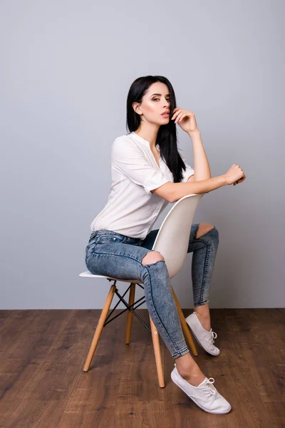 Mooie jonge vrouw die zich voordeed en leunend op de achterkant van de stoel — Stockfoto