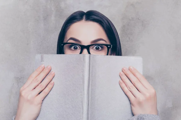 Chytrá Mladá krásná dívka v brýlích stojí na šedé poza — Stock fotografie