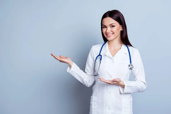 Freundlich lächelnde junge Ärztin zeigt etwas Heiles — Stockfoto