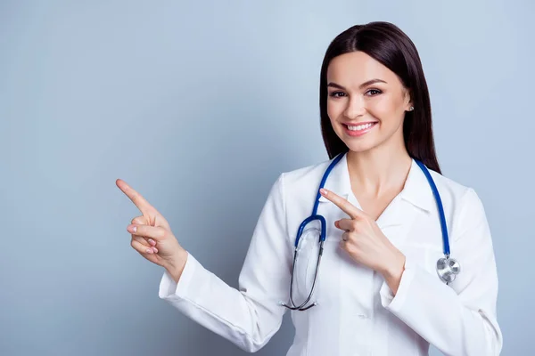 Vänliga leende unga kvinnliga läkare pekar med fingret till den — Stockfoto