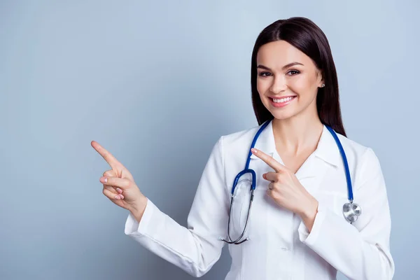 Amigável sorridente jovem médico apontando com o dedo para o — Fotografia de Stock