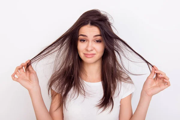 Menina triste mostrando seu cabelo danificado enquanto em pé backgrou branco — Fotografia de Stock