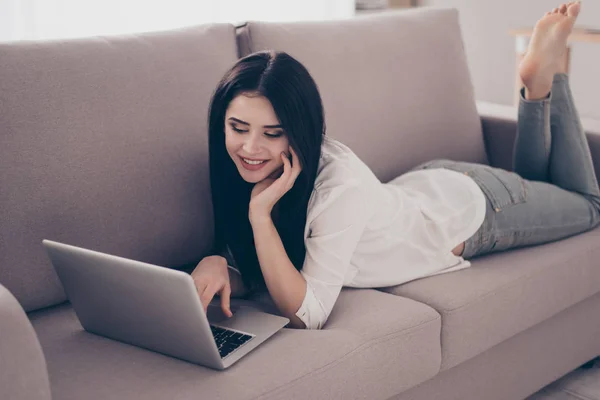 Giovane bella ragazza carina si trova sul divano con il computer portatile, t — Foto Stock