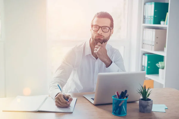 Schöner junger Geschäftsmann sitzt am Tisch im lichtdurchfluteten Büro, — Stockfoto