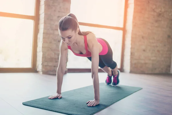 Concentrated girl doing her plank work out to keep abs fit. She — Stock Photo, Image