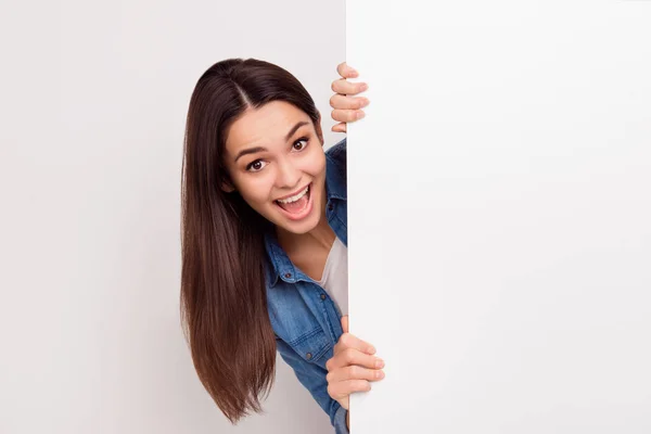 Feliz menina surpreendida está saindo do banner branco em branco — Fotografia de Stock