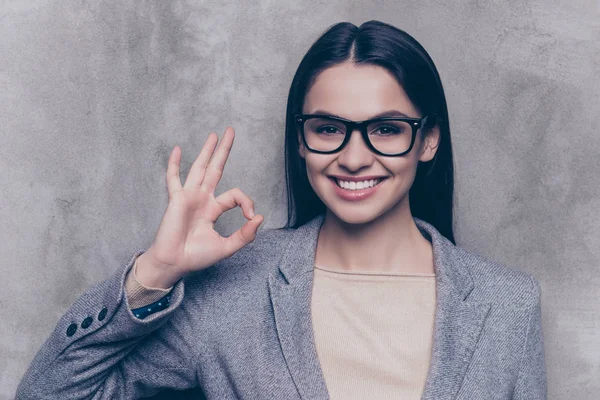 Portret szczęśliwy dość młoda kobieta w okularach stoi na szary b — Zdjęcie stockowe