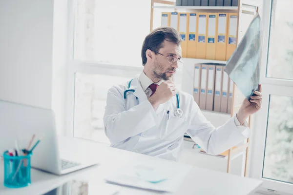 Portret van een arts kijken naar een radiografie. Hij is gericht, le — Stockfoto