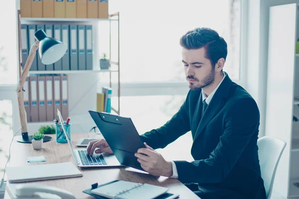 Koncentrerad ungersven i svart kostym sitter på fliken — Stockfoto