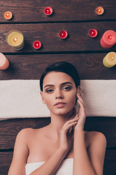 Leuke ontspannen jonge vrouw in spa salon over handdoek te leggen — Stockfoto