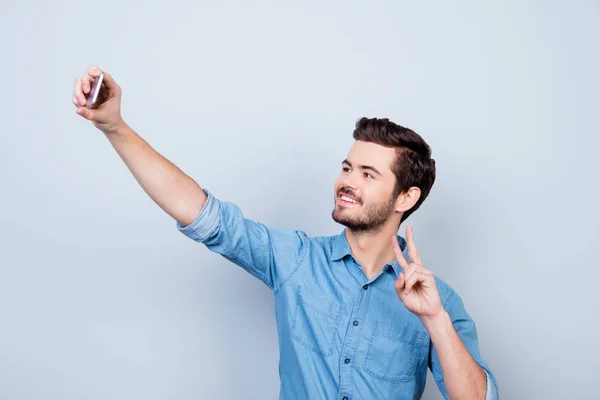 Красивый улыбающийся молодой человек делает селфи на смартфоне и GE — стоковое фото