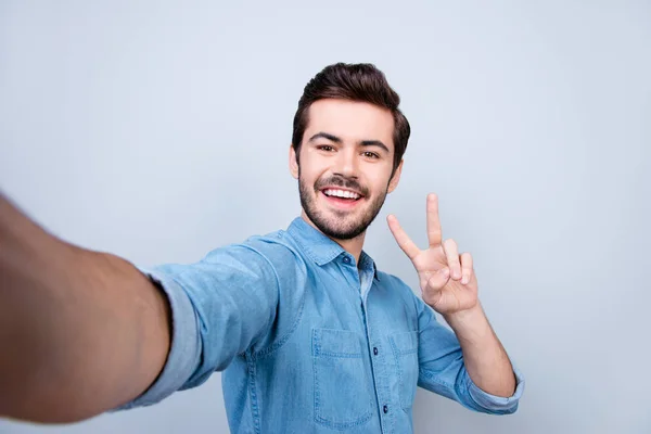 Przystojny uśmiechający się młody człowiek jest Dokonywanie selfie na smartfonie i ge — Zdjęcie stockowe