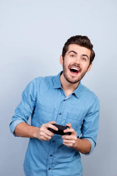 Retrato de un joven sosteniendo un joystick y jugando videojuegos. H —  Fotos de Stock