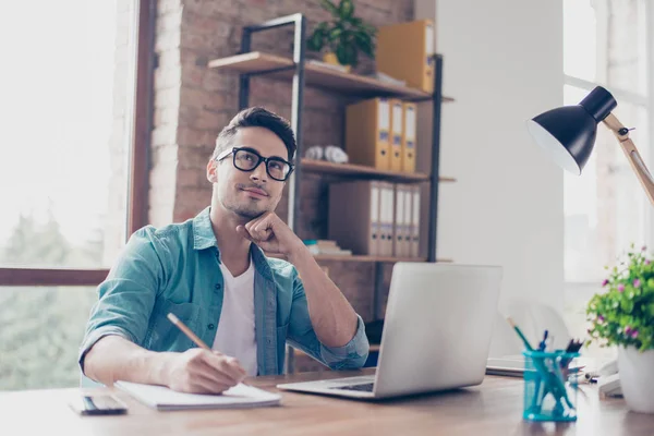 Portrait of minded young student sitting at the table in front o — Stock Photo, Image