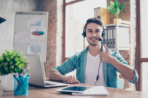 Sorrindo jovem operador de call center sentado à mesa e s — Fotografia de Stock