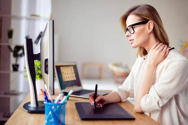 Concentrated young woman in glasses retouching photo for a long — Stock Photo, Image