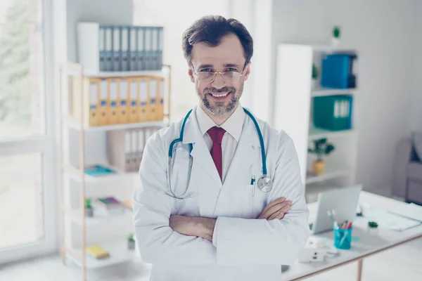 Succesvolle arts in witte uniform staat op zijn werkplek — Stockfoto