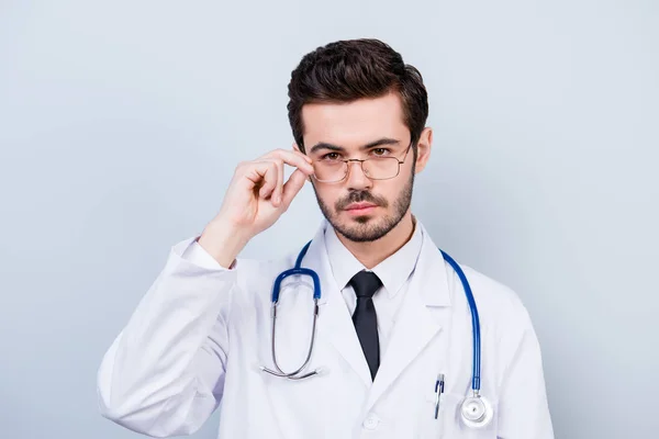 Retrato de um jovem médico sério e confiante tocando seus óculos — Fotografia de Stock