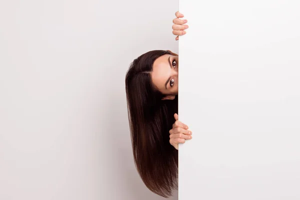 Linda mujer joven con el pelo largo mirando alrededor de detrás de blanco —  Fotos de Stock