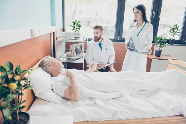 El joven médico y la enfermera están visitando a un paciente de edad avanzada en la m brillante — Foto de Stock