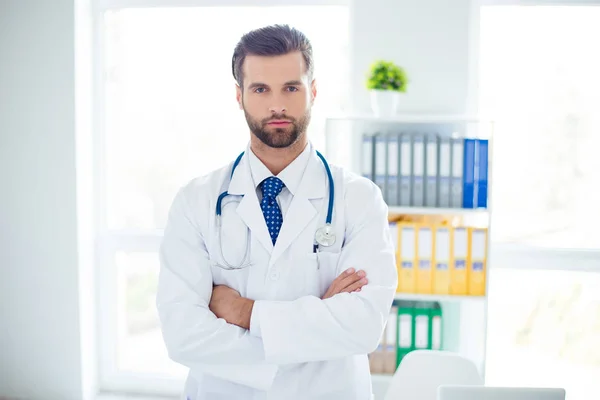 Portrait of serious strict doctor in white coat standing with cr — Stok Foto