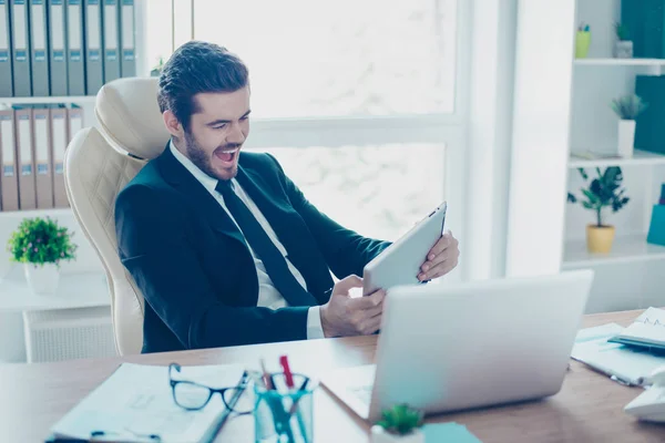 Vrolijke jonge zakenman is een spel op zijn tablet in varen uit — Stockfoto