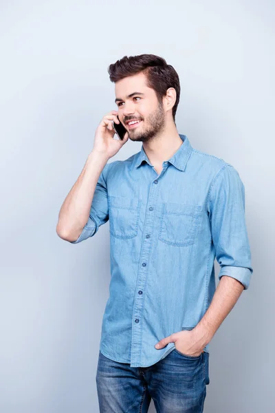 Zasněný pohledný mladík mluví do telefonu, s úsměvem. On i — Stock fotografie