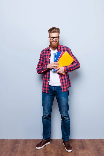 Веселий молодий нервово-червоний бородатий студент, що стоїть з книгами на — стокове фото