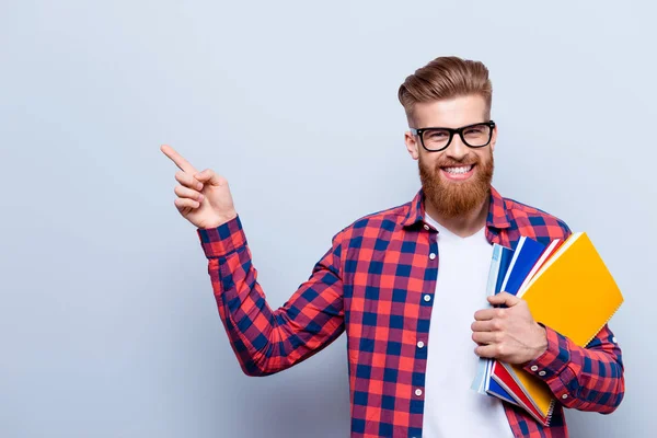 Sonriente joven nerd rojo barbudo elegante estudiante está de pie con —  Fotos de Stock