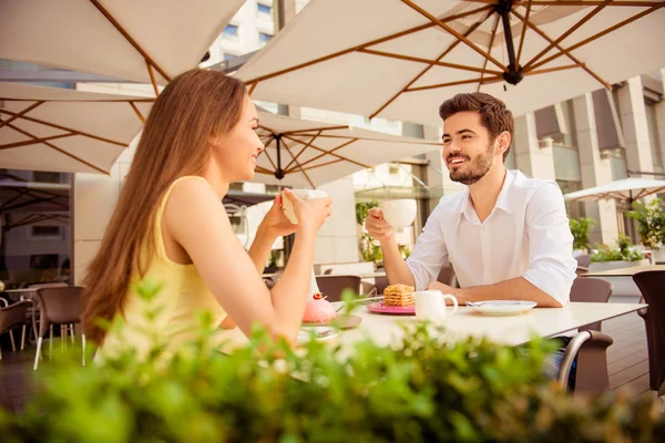 Young happy couple is sitting in light cafe`s terrace outdoors o — Stock Photo, Image