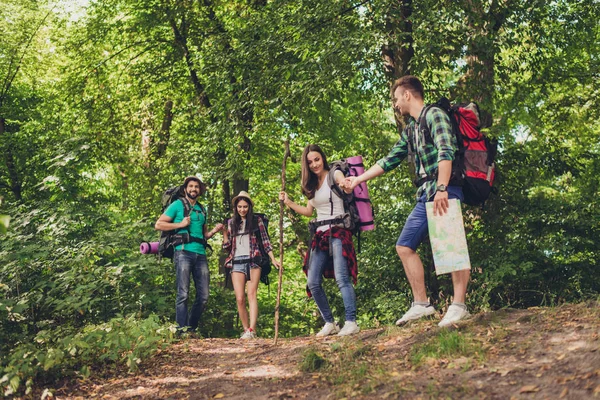 Quatro turistas se perderam na floresta, tentando encontrar o caminho, parecendo sérios e focados, todos tendo mochilas, companheiros, todos necessários para passar a noite — Fotografia de Stock