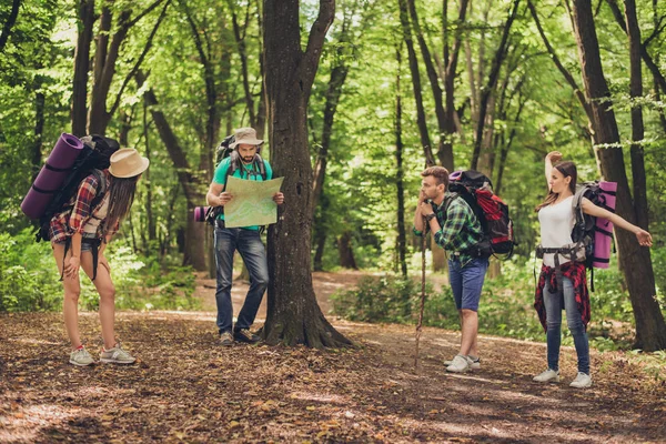 Четверо туристів зупинилися для відпочинку в лісі, тримаючи карту, трінь — стокове фото