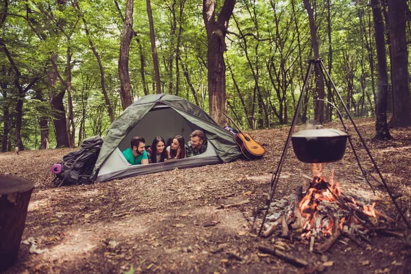 Primer plano retrato recortado de cuatro amigos alegres en el verano agradable madera. Son excursionistas, caminando y recogiendo lugar para acampar, abrazando, posando para la foto — Foto de Stock