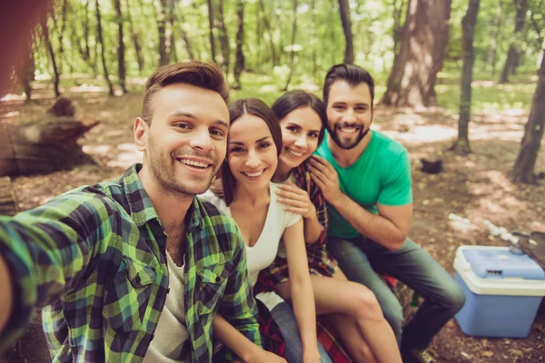 Närbild av beskurna porträtt av fyra glada vänner i sommar fin trä. De är vandrare, promenader och plocka plats för camping, allomfattande, poserar för fotot — Stockfoto