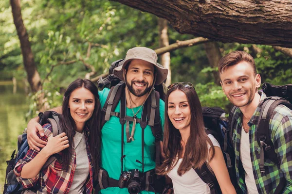 Close up cropped portrait of four cheerful  friends in the summer nice wood. They are hikers, walking and picking place for camping, embracing, posing for photo — Stock Photo, Image