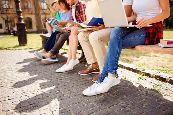 Prise de vue rapprochée à angle bas des jambes de six étudiants, assis — Photo