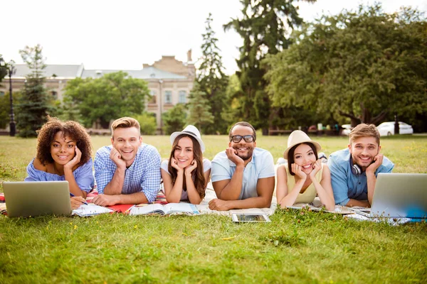 Είναι πιο εύκολο μαζί! Έξι χαρούμενα συμμαθητές κάθονται σε καρό στο πράσινο γρασίδι στο πάρκο άνοιξη κοντά στην πανεπιστημιούπολη και μελέτη, προετοιμασία για εξετάσεις, δοκιμές, ψάχνει στην κάμερα και χαμογελαστός — Φωτογραφία Αρχείου