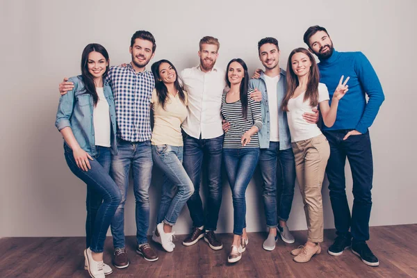 Oito amigos felizes estão posando perto da parede, sorrindo e gestur — Fotografia de Stock