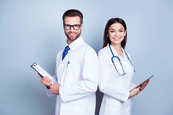 Dos colegas médicos con batas blancas sobre fondo puro, sosteniendo — Foto de Stock