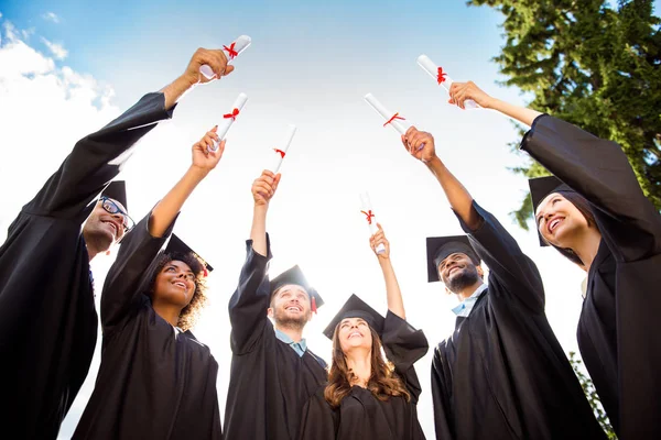 Seis exitosos graduados emocionados con túnicas negras están mirando t —  Fotos de Stock