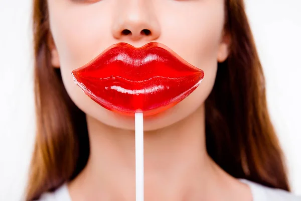 Concepto de cirugía plástica. Recortado de cerca la foto de la mujer joven sosteniendo grandes labios rojos en forma de caramelo cerca de la boca sobre fondo blanco — Foto de Stock