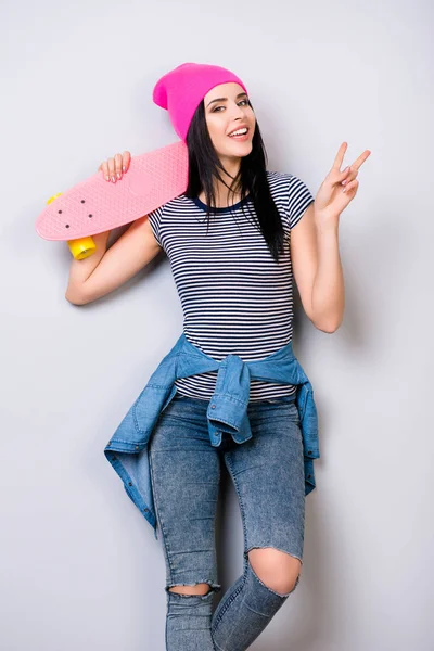 Retrato vertical de jovem mulher sorridente com skate em seu — Fotografia de Stock