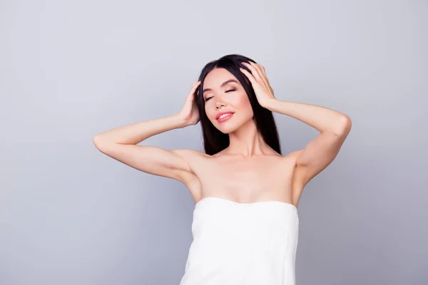 Hermosa chica asiática joven, envuelta en una toalla blanca está tocando su cabello sobre fondo gris claro, tan encantador y feliz —  Fotos de Stock