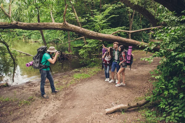 Fotógrafo masculino está tirando fotos de seus três amigos perto do lago na madeira da primavera, natureza tão bonita! Eles são turistas, caminhando trilha selva — Fotografia de Stock