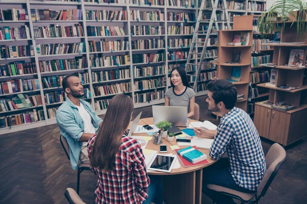 Grupo internacional de quatro jovens estudantes inteligentes focados bookwo — Fotografia de Stock