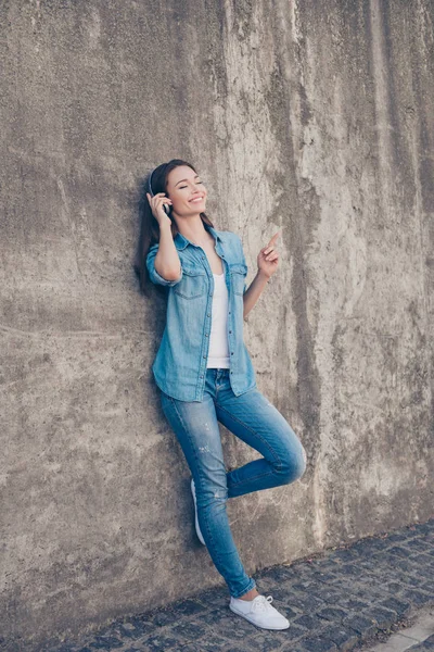 Njut av musiken! Ung söt hipster lutar i betongväggen — Stockfoto