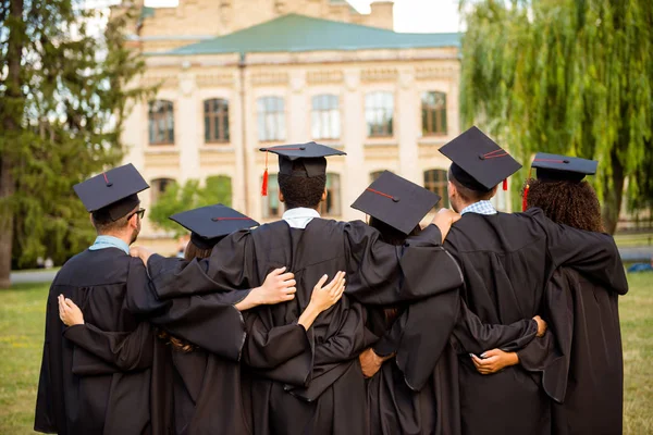Vista posterior de seis graduados exitosos en túnicas negras, vinculación, i — Foto de Stock
