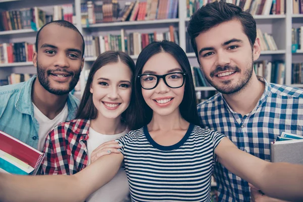 Selfie mania! Quattro studenti internazionali con sorrisi radiosi ar — Foto Stock