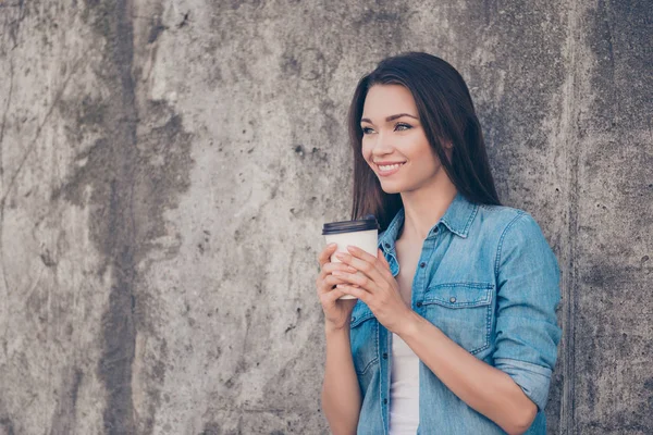 Buongiorno! Buongiorno! Allegro piuttosto giovane signora bruna serena sta prendendo il tè caldo vicino al muro di cemento fuori, sorridente, indossando abbigliamento casual accogliente — Foto Stock